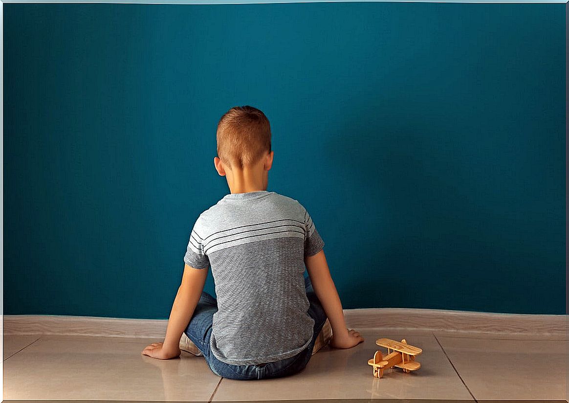 Boy with autism sitting in front of the wall