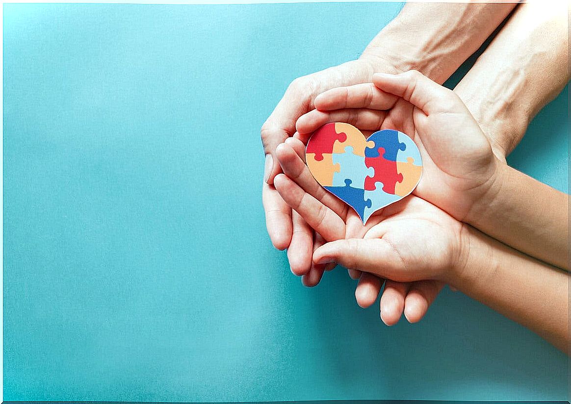 Hands of a mother and daughter with a heart with the colors of autism