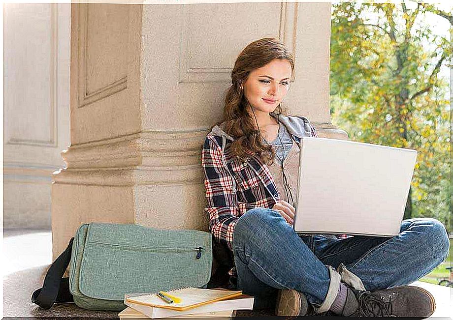 girl leaning on a pillar and using a computer trying to fight boredom while studying