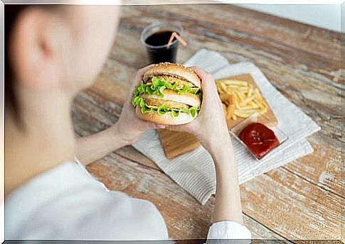 Woman eating hamburger for emotional eating problems