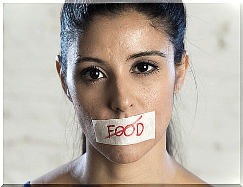 Woman with a sign in her mouth in which the word food is crossed out