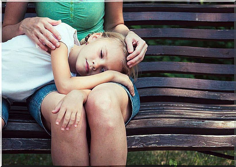 Sad daughter with her head resting on the legs of her mother who suffers the wound of separation