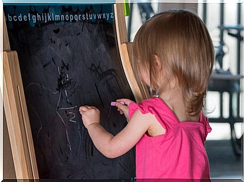 Little girl writing on a blackboard with both hands